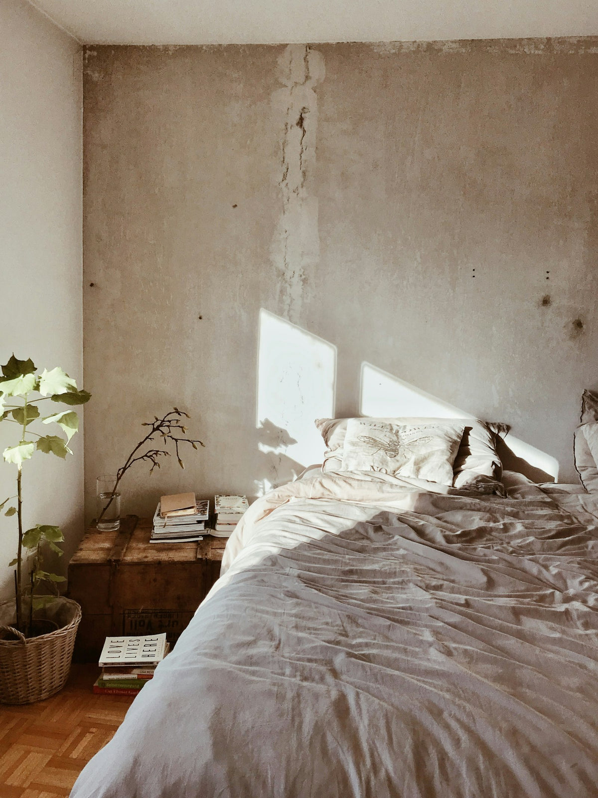 Cozy bed with linen sheets and plant